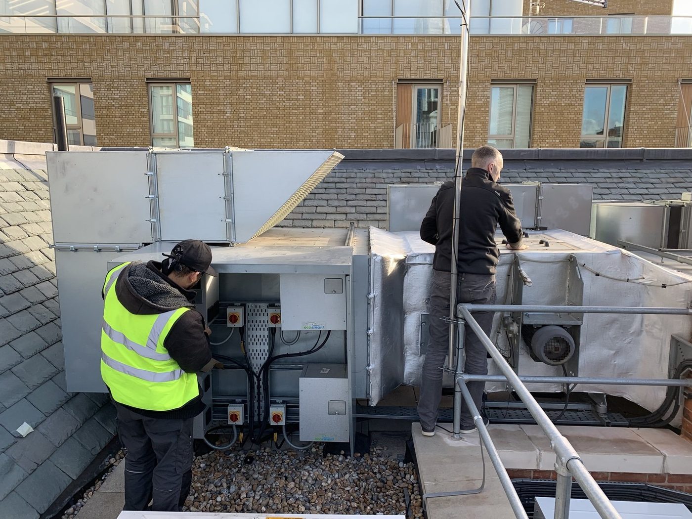 TJB engineers on a commercial rooftop plant deck, working on a large AHU installation